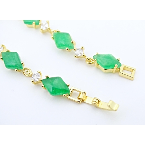 673 - A gilt metal bracelet set with jade green coloured stones and white stones. Approx 7 1/2