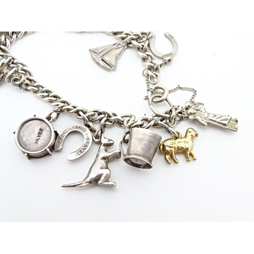 675 - A silver and white metal charm bracelet with various charms including a 9ct gold charm formed as a s... 