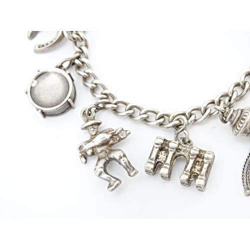 675 - A silver and white metal charm bracelet with various charms including a 9ct gold charm formed as a s... 