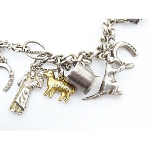 675 - A silver and white metal charm bracelet with various charms including a 9ct gold charm formed as a s... 