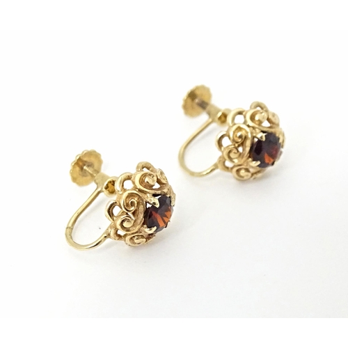 679 - 9ct gold earrings set with central garnets. Approx 1/4