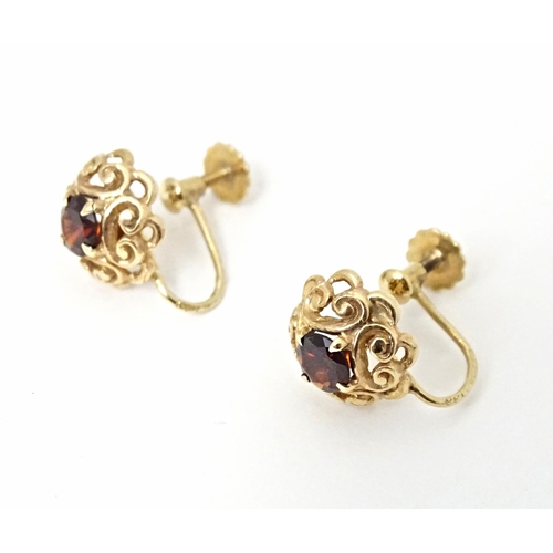 679 - 9ct gold earrings set with central garnets. Approx 1/4