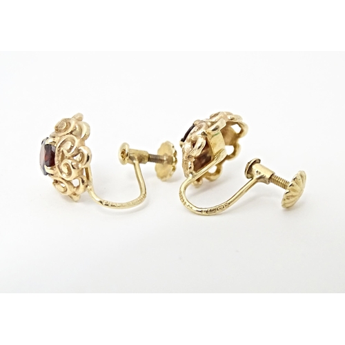 679 - 9ct gold earrings set with central garnets. Approx 1/4