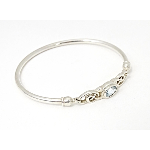 682 - A silver and white metal bangle formed bracelet set with aquamarine coloured stone