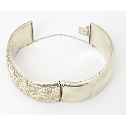 683 - A silver bracelet of bangle form with engraved acanthus scroll decoration. Hallmarked Birmingham 196... 