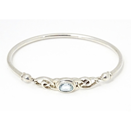 682 - A silver and white metal bangle formed bracelet set with aquamarine coloured stone