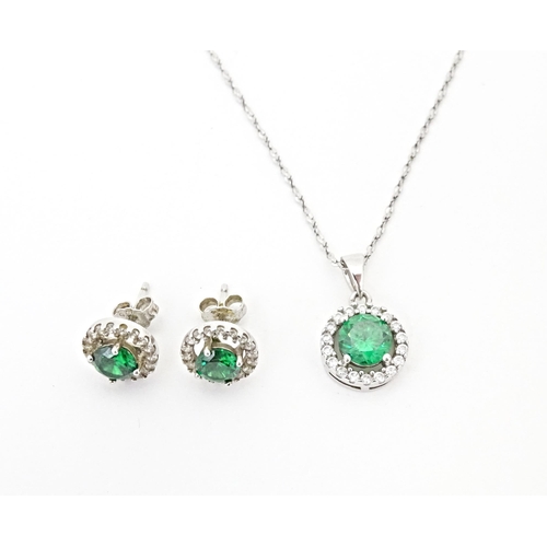 702 - A silver suite of jewellery comprising pendant and stud earrings set with central green stone border... 