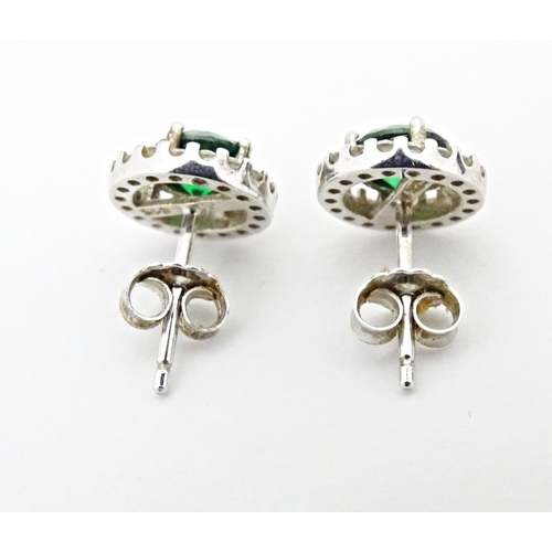 702 - A silver suite of jewellery comprising pendant and stud earrings set with central green stone border... 