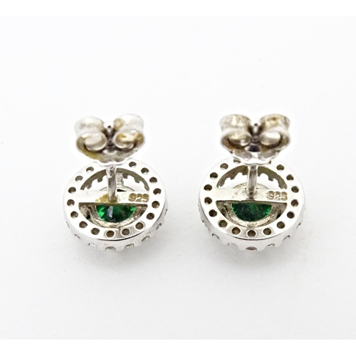 702 - A silver suite of jewellery comprising pendant and stud earrings set with central green stone border... 