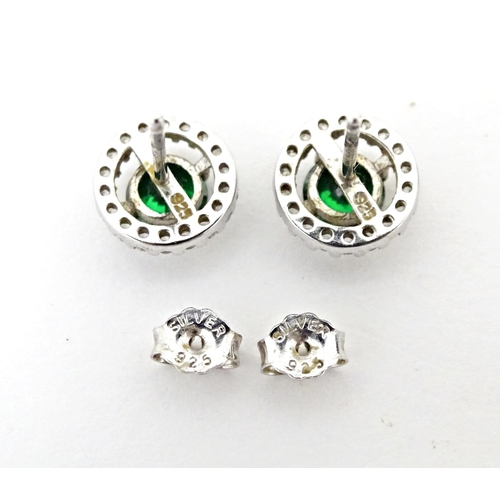 702 - A silver suite of jewellery comprising pendant and stud earrings set with central green stone border... 