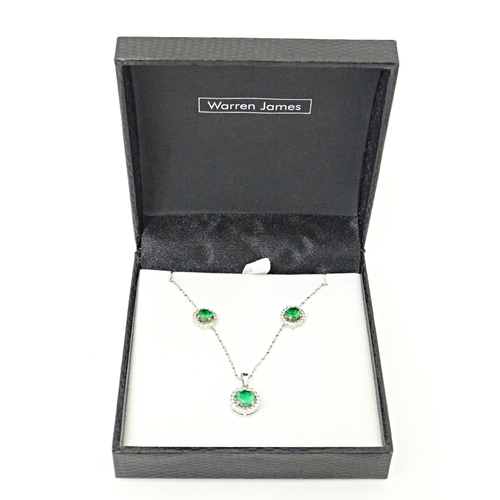 702 - A silver suite of jewellery comprising pendant and stud earrings set with central green stone border... 