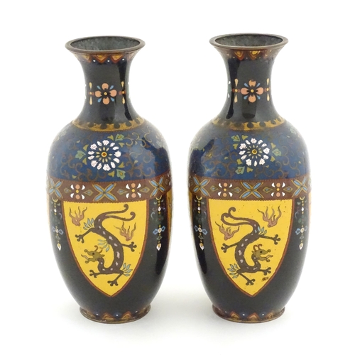 980 - A pair of Oriental cloisonne vases decorated with panels of dragons and phoenix birds, the shoulders... 