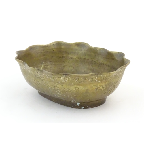 993 - A Chinese oval brass bowl with a lobed rim, decorated with incised dragons and flaming pearl amongst... 