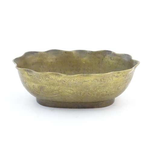 993 - A Chinese oval brass bowl with a lobed rim, decorated with incised dragons and flaming pearl amongst... 