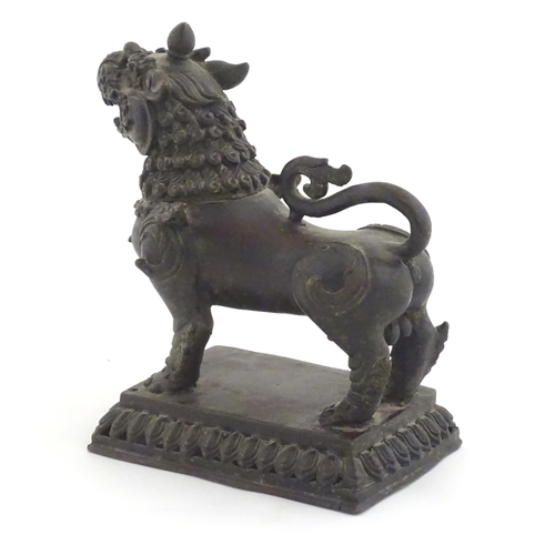 994 - An Oriental cast temple lion with scrolled tail on a pierced rectangular base. Approx. 7 1/2