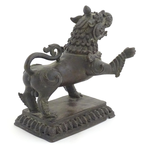 994 - An Oriental cast temple lion with scrolled tail on a pierced rectangular base. Approx. 7 1/2