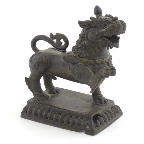 994 - An Oriental cast temple lion with scrolled tail on a pierced rectangular base. Approx. 7 1/2