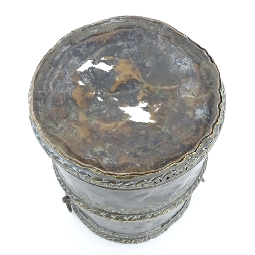 1056 - An Eastern copper lidded container of cylindrical form with twin handles, applied banded decoration ... 