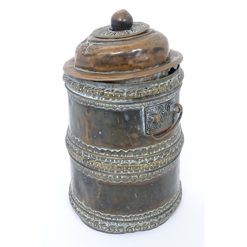 1056 - An Eastern copper lidded container of cylindrical form with twin handles, applied banded decoration ... 