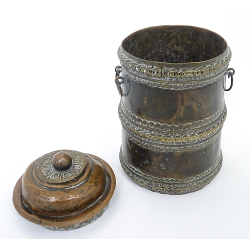 1056 - An Eastern copper lidded container of cylindrical form with twin handles, applied banded decoration ... 