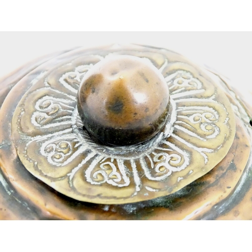 1056 - An Eastern copper lidded container of cylindrical form with twin handles, applied banded decoration ... 