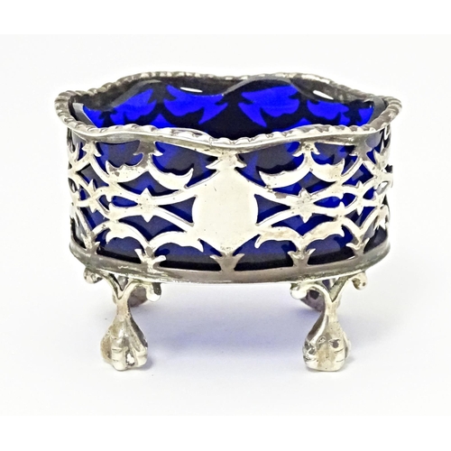 327 - A Victorian silver salt with pierced decoration and blue glass liner, standing on four ball and claw... 