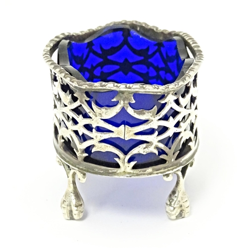 327 - A Victorian silver salt with pierced decoration and blue glass liner, standing on four ball and claw... 