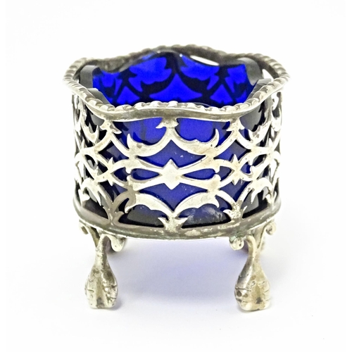 327 - A Victorian silver salt with pierced decoration and blue glass liner, standing on four ball and claw... 