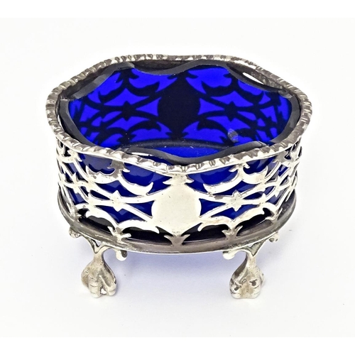 327 - A Victorian silver salt with pierced decoration and blue glass liner, standing on four ball and claw... 