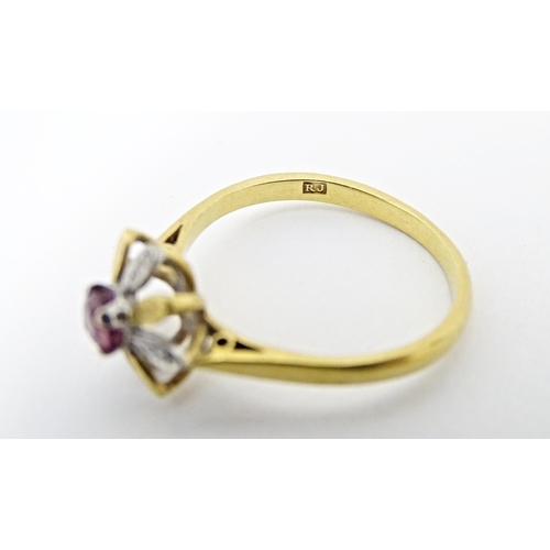 608 - An 18ct gold ring set with a central ruby bordered by chip set diamonds in a floral setting. Ring si... 