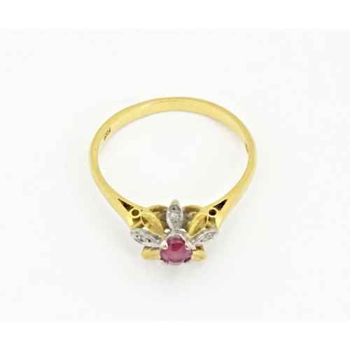 608 - An 18ct gold ring set with a central ruby bordered by chip set diamonds in a floral setting. Ring si... 