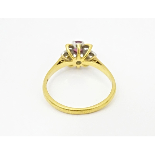 608 - An 18ct gold ring set with a central ruby bordered by chip set diamonds in a floral setting. Ring si... 