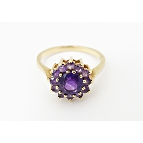 614 - A 9ct gold ring set with central amethyst bordered by further amethysts. Ring size approx. N