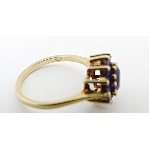 614 - A 9ct gold ring set with central amethyst bordered by further amethysts. Ring size approx. N