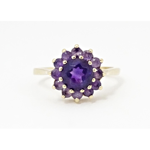 614 - A 9ct gold ring set with central amethyst bordered by further amethysts. Ring size approx. N