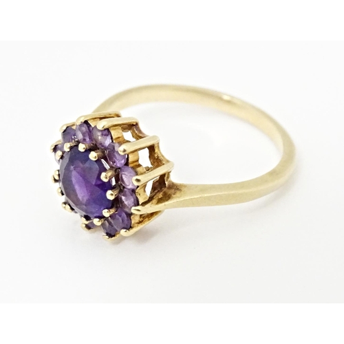 614 - A 9ct gold ring set with central amethyst bordered by further amethysts. Ring size approx. N