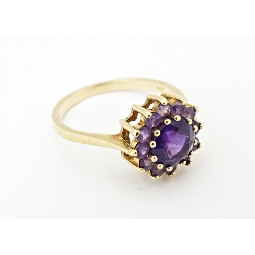 614 - A 9ct gold ring set with central amethyst bordered by further amethysts. Ring size approx. N