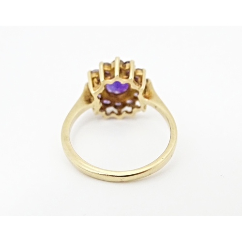 614 - A 9ct gold ring set with central amethyst bordered by further amethysts. Ring size approx. N