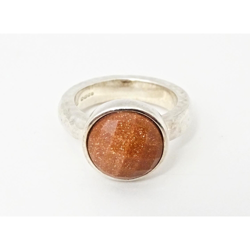 767 - A hallmarked silver ring with hammered finish and set with facet cut goldstone, hallmarks for London... 