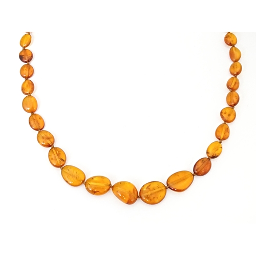 717 - Three various amber coloured bead necklaces. The longest also set with lapis lazuli beads. Approx 20... 