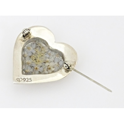 725 - A silver heart shaped brooch with forget me not flower decoration to centre 1 1/4