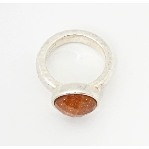 767 - A hallmarked silver ring with hammered finish and set with facet cut goldstone, hallmarks for London... 