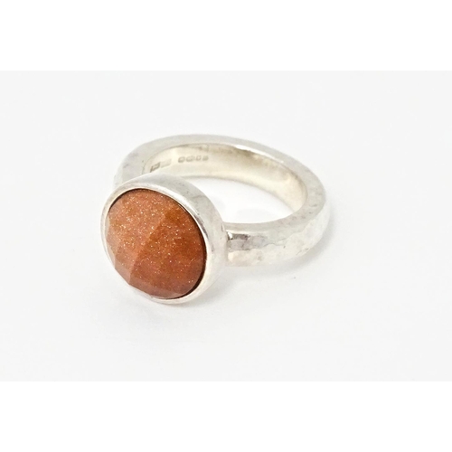 767 - A hallmarked silver ring with hammered finish and set with facet cut goldstone, hallmarks for London... 