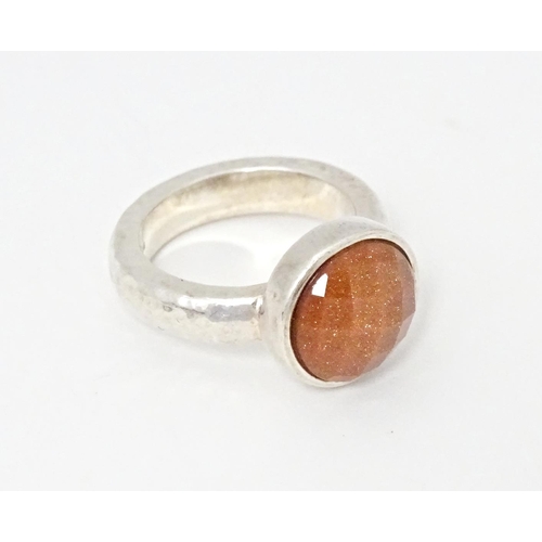 767 - A hallmarked silver ring with hammered finish and set with facet cut goldstone, hallmarks for London... 