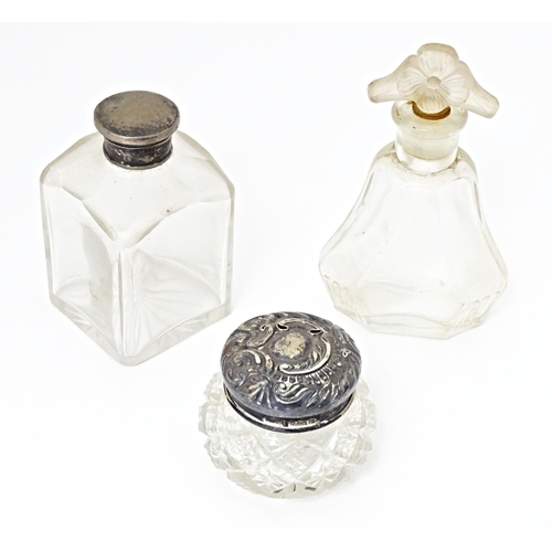 447 - Three various glass scent / dressing table bottles, one with Hallmarked silver top. The tallest 4 1/... 