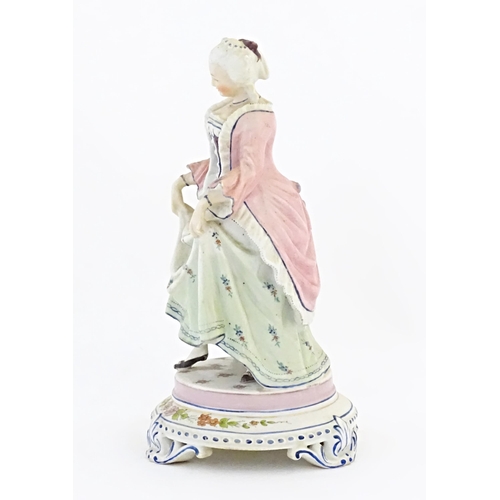 153 - A Continental model of a lady holding her dress skirt, standing on a circular base with floral detai... 