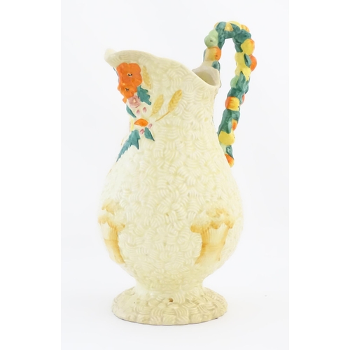 79 - A Clarice Cliff harvest jug decorated with moulded fruit handle, the baluster body decorated with re... 