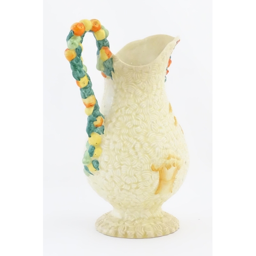 79 - A Clarice Cliff harvest jug decorated with moulded fruit handle, the baluster body decorated with re... 