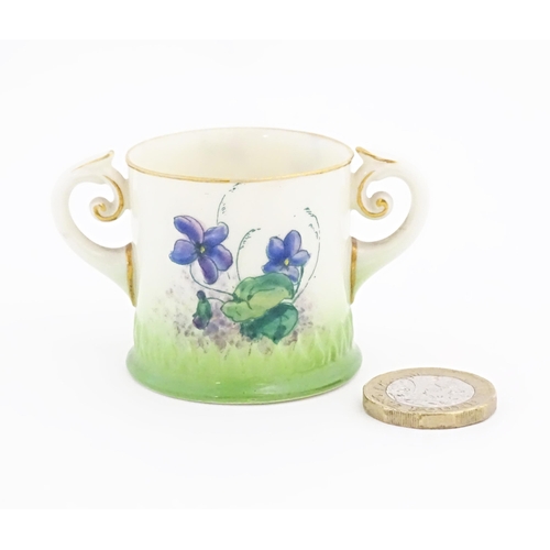 105 - A miniature Royal Worcester loving cup with scrolled handles, decorated with flowers and foliage. Ma... 