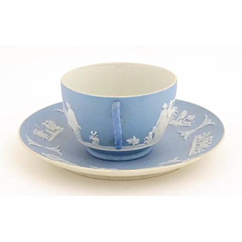 121 - A Wedgwood Jasperware tea cup and saucer decorated with classical figures in relief. Cup approx. 2